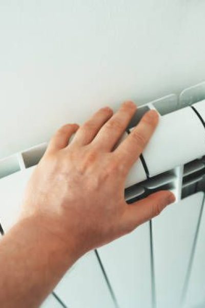 Man's hand checking temperature of heating radiator.